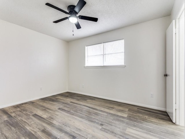 empty room with ceiling fan, wood-type flooring, and a textured ceiling