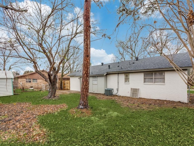 back of house with central air condition unit and a yard