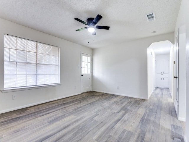 empty room with a textured ceiling, light hardwood / wood-style flooring, and ceiling fan