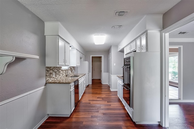 kitchen featuring sink, white cabinetry, dark stone countertops, a textured ceiling, and dark hardwood / wood-style flooring