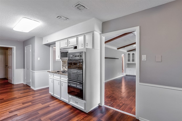 kitchen with white cabinets, a textured ceiling, stainless steel gas stovetop, and dark wood-type flooring