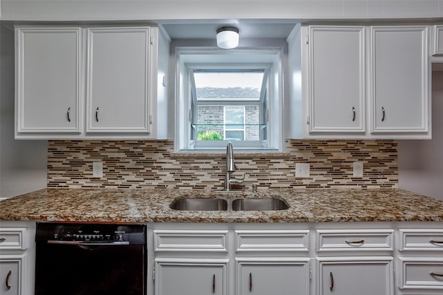 kitchen featuring white cabinets, light stone counters, sink, and black dishwasher