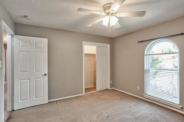 unfurnished bedroom featuring a textured ceiling, ceiling fan, light carpet, and a closet