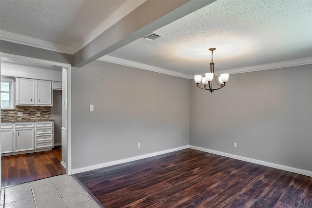 unfurnished dining area with a textured ceiling, dark hardwood / wood-style flooring, an inviting chandelier, and crown molding