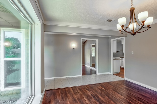 unfurnished room with an inviting chandelier, hardwood / wood-style floors, and a textured ceiling