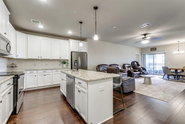 kitchen featuring white cabinetry, an island with sink, decorative light fixtures, ceiling fan with notable chandelier, and appliances with stainless steel finishes