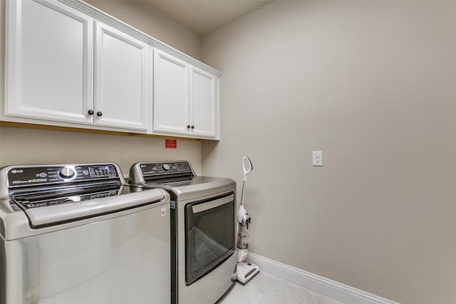 laundry area featuring washing machine and clothes dryer, light tile patterned flooring, and cabinets