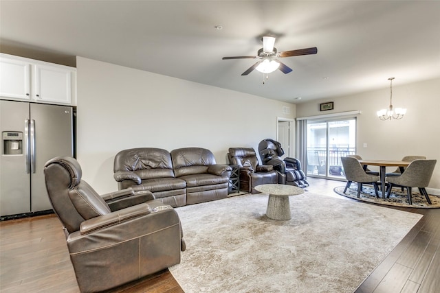 living room with ceiling fan with notable chandelier and dark hardwood / wood-style floors