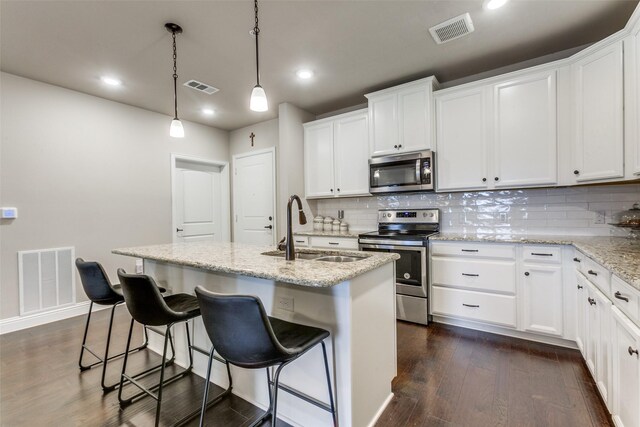 kitchen featuring white cabinets, appliances with stainless steel finishes, a kitchen island with sink, and sink