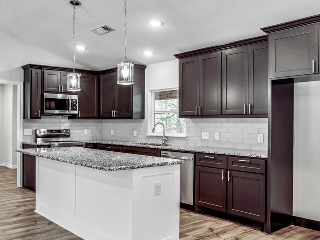 kitchen featuring tasteful backsplash, hanging light fixtures, a center island, ceiling fan, and light hardwood / wood-style floors