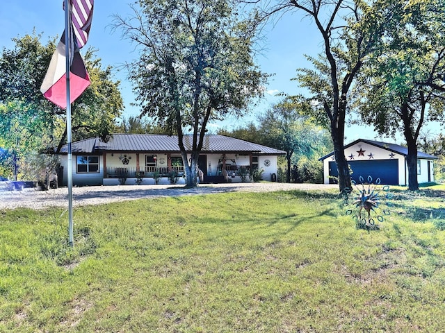 view of front of home featuring a front yard, a garage, a porch, and an outbuilding