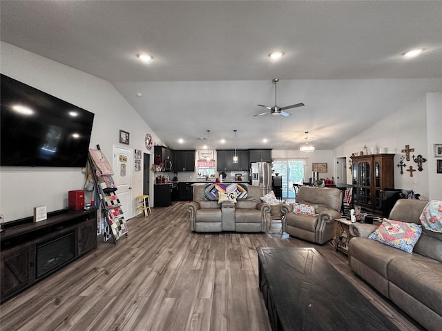 living room featuring hardwood / wood-style flooring, ceiling fan with notable chandelier, and vaulted ceiling