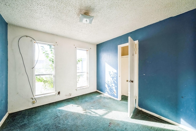 carpeted empty room with a textured ceiling