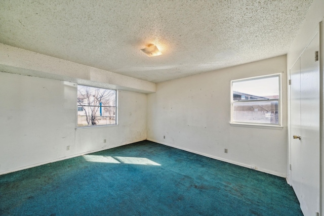 empty room with a textured ceiling and dark colored carpet