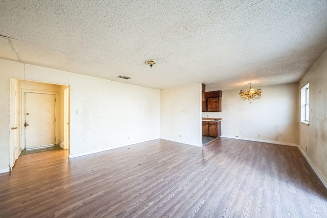 unfurnished living room featuring a notable chandelier, a textured ceiling, and hardwood / wood-style flooring