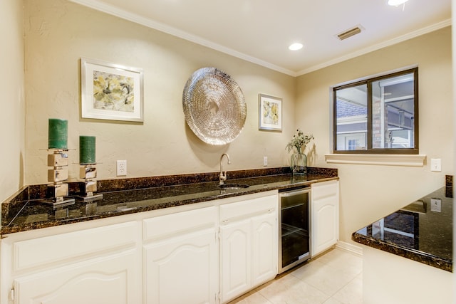 interior space featuring a sink, dark stone countertops, beverage cooler, and crown molding