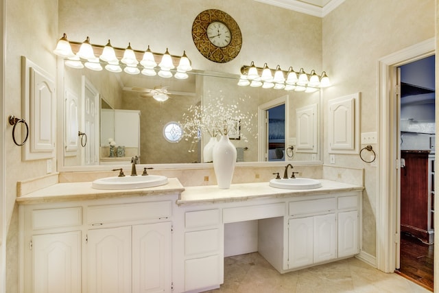full bath featuring double vanity, ceiling fan, crown molding, and a sink