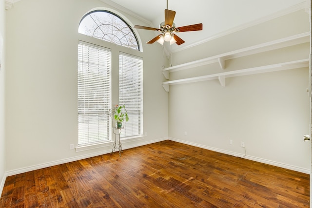 empty room with a wealth of natural light, baseboards, hardwood / wood-style floors, and a ceiling fan