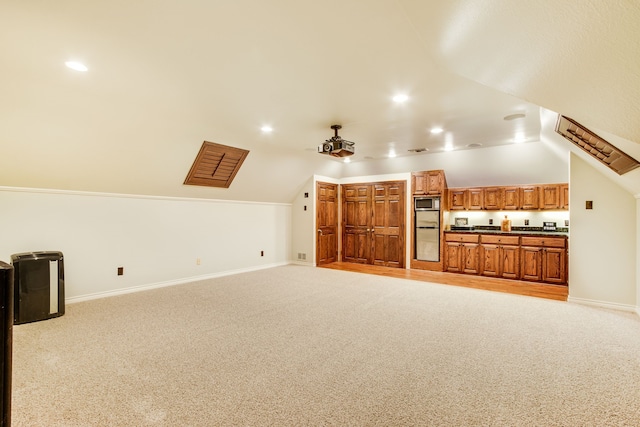 unfurnished living room featuring vaulted ceiling, ceiling fan, and light colored carpet