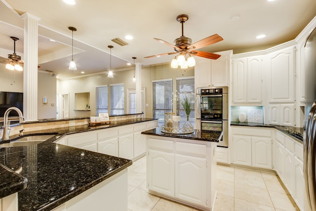 kitchen featuring white cabinetry, stainless steel double oven, dark stone countertops, a kitchen island, and sink