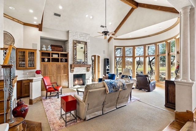 carpeted living room with a fireplace, beam ceiling, high vaulted ceiling, and ornate columns