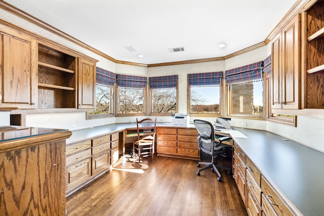 office area with dark wood-type flooring, ornamental molding, and built in desk