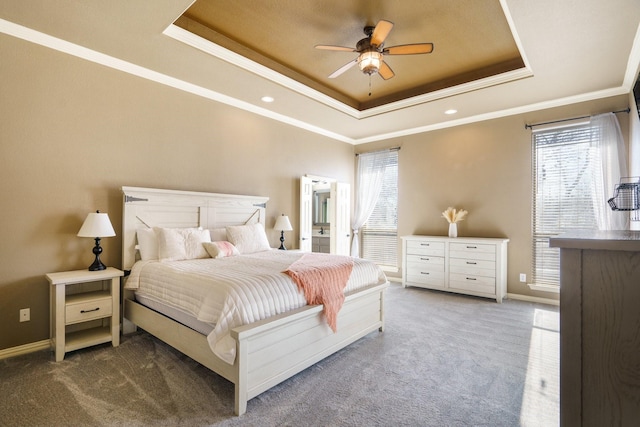 bedroom featuring carpet flooring, multiple windows, a tray ceiling, and ceiling fan