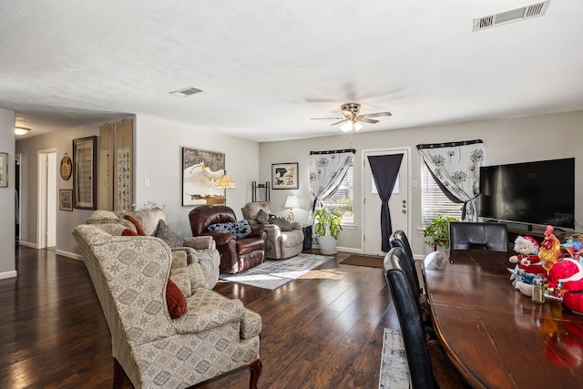 living room with ceiling fan, a textured ceiling, and dark wood-type flooring