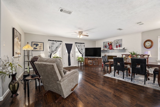 living room with a textured ceiling, ceiling fan, and dark wood-type flooring