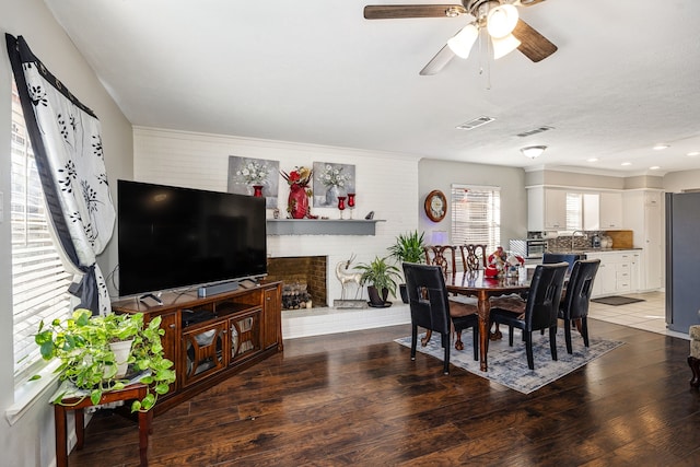 dining room featuring ceiling fan, sink, dark hardwood / wood-style floors, and a brick fireplace