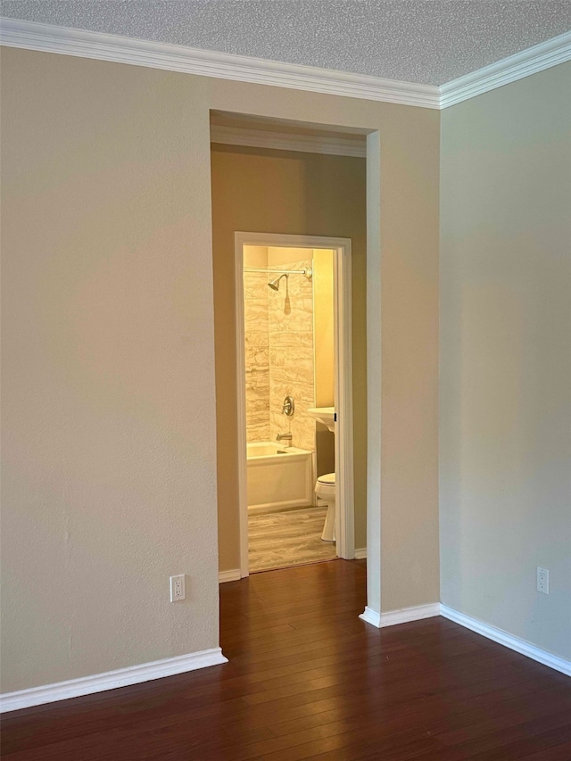 empty room with crown molding, dark hardwood / wood-style floors, and a textured ceiling