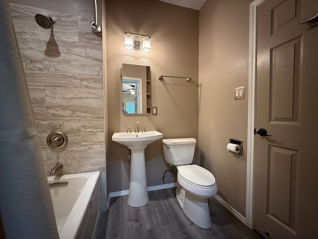 bathroom featuring toilet, tiled shower / bath combo, and hardwood / wood-style floors