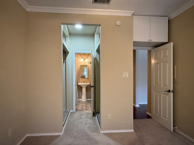 corridor with ornamental molding, sink, and light colored carpet