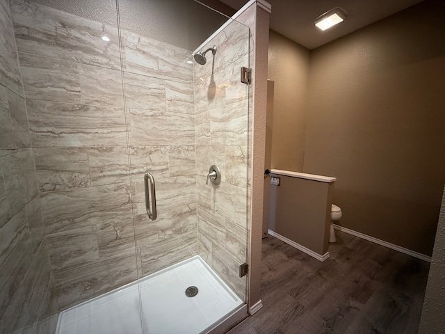 bathroom with an enclosed shower, hardwood / wood-style floors, and toilet