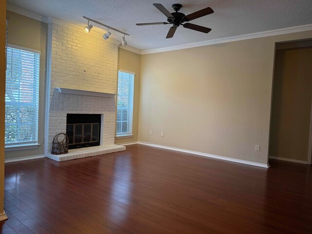 unfurnished living room featuring a fireplace, a textured ceiling, rail lighting, and crown molding