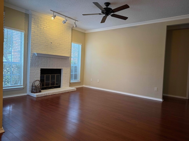 unfurnished living room featuring crown molding, dark hardwood / wood-style flooring, a brick fireplace, and a textured ceiling