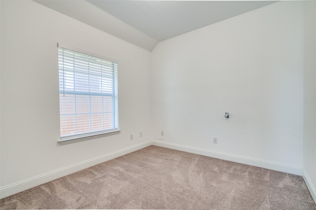 unfurnished room featuring vaulted ceiling and light colored carpet