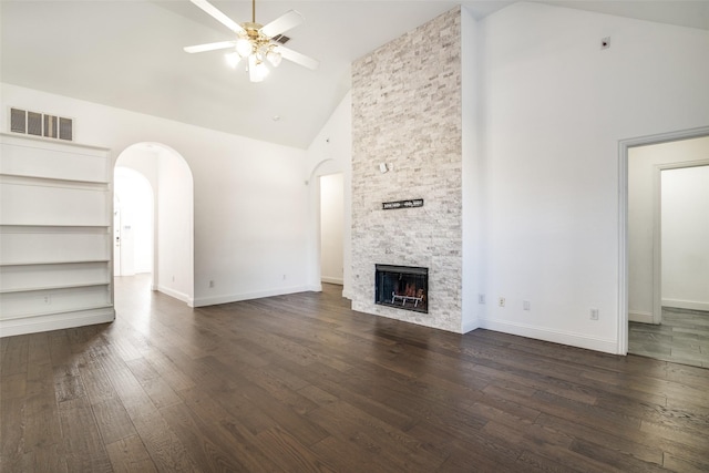 unfurnished living room with dark wood-type flooring, high vaulted ceiling, ceiling fan, and a stone fireplace