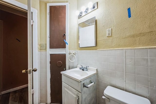 bathroom featuring vanity, tile walls, and toilet