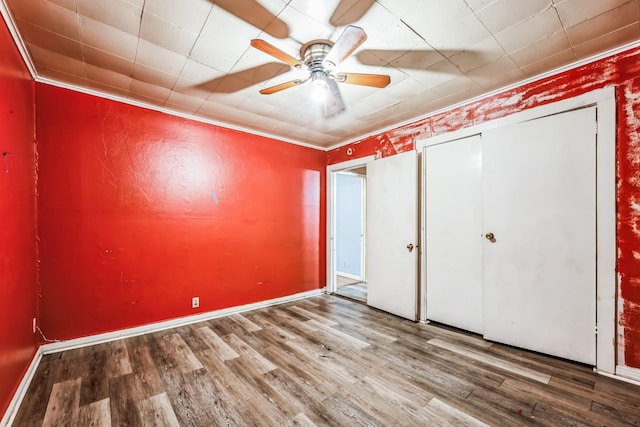 unfurnished bedroom featuring ornamental molding, hardwood / wood-style floors, ceiling fan, and a closet