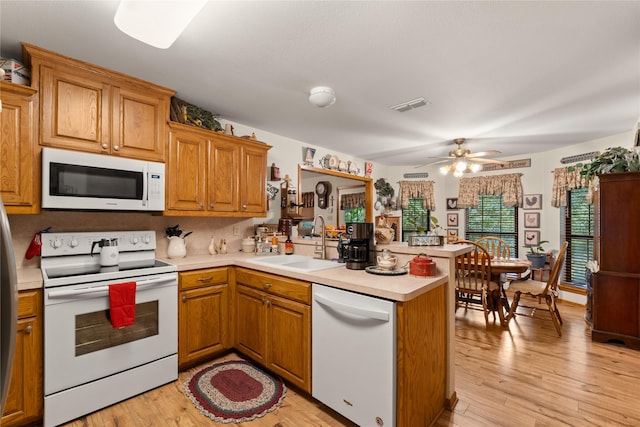 kitchen featuring kitchen peninsula, white appliances, light hardwood / wood-style flooring, and sink