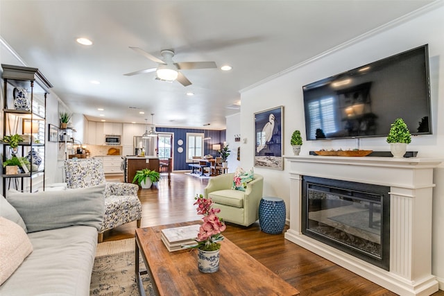 living room with hardwood / wood-style floors, ceiling fan, and ornamental molding