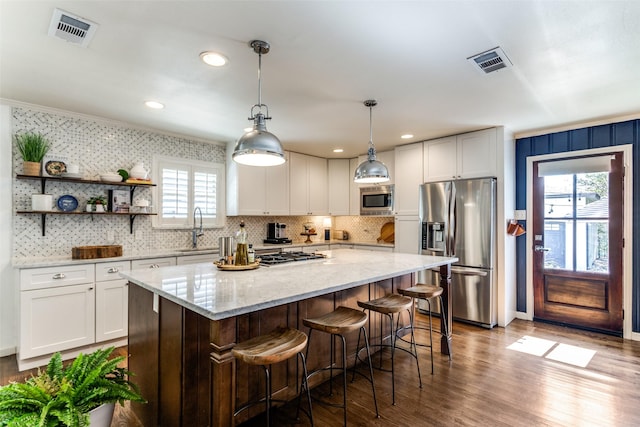 kitchen featuring a center island, stainless steel appliances, white cabinetry, and sink