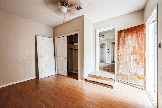 unfurnished bedroom featuring ceiling fan, wood-type flooring, a textured ceiling, and a closet