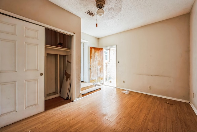 unfurnished bedroom with wood-type flooring, a textured ceiling, a closet, and ceiling fan