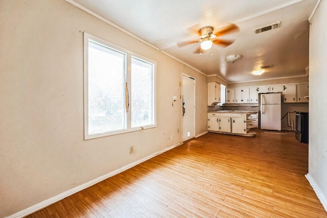 kitchen featuring ornamental molding, light hardwood / wood-style floors, ceiling fan, white cabinets, and white fridge