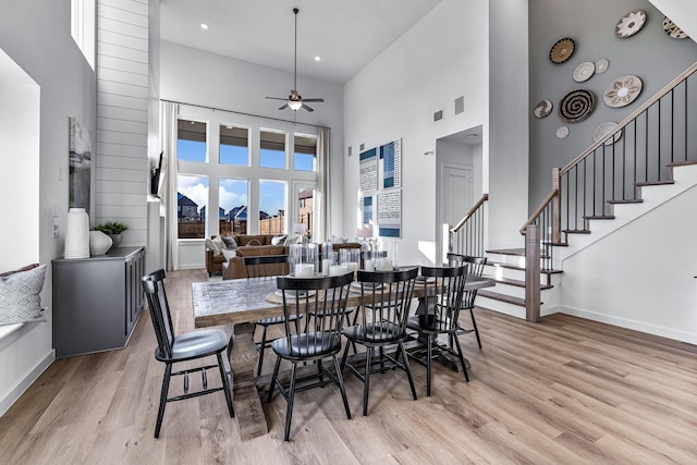 dining area with a high ceiling, light wood-type flooring, and ceiling fan