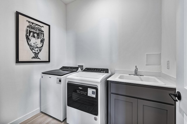 washroom with cabinets, washer and clothes dryer, sink, and light hardwood / wood-style flooring