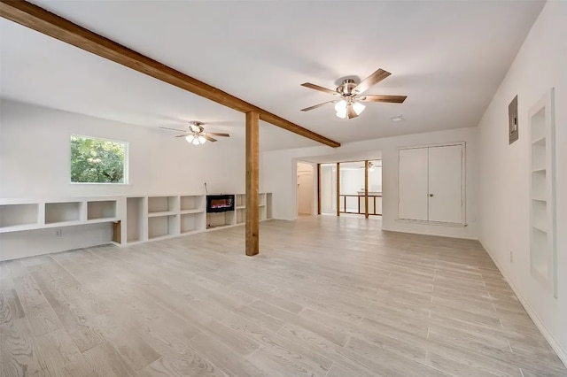 unfurnished room featuring ceiling fan, a fireplace, beamed ceiling, and light hardwood / wood-style flooring