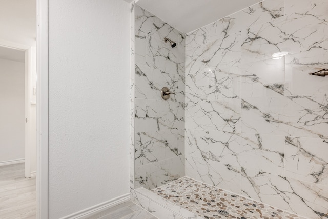 bathroom with tiled shower and hardwood / wood-style flooring